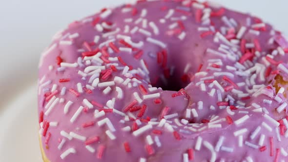 Sweet dessert close-up. Donut pastry in sugar glaze rotates on a plate.Macro.