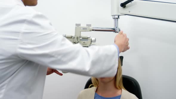 Smiling optometrist examining female patient on phoropter