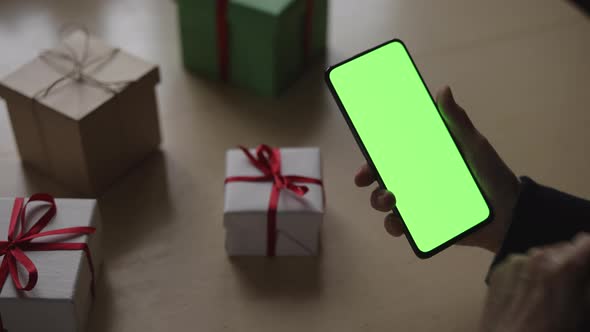 Handheld Shot of Old Female Hands Holding Smartphone with Green Screen and Celebrating Holiday