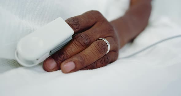 Close-up of pulse oximetry on African american male patient hand in the ward at hospital