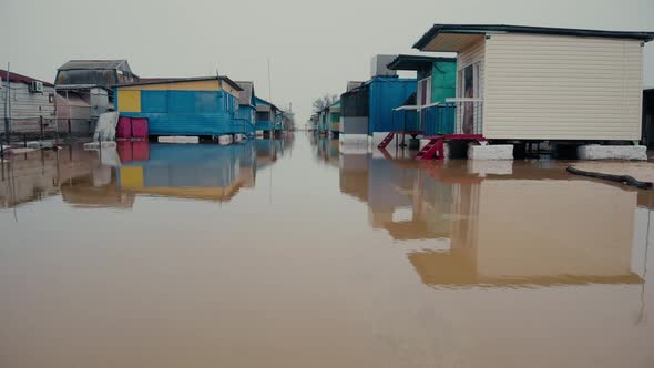 Aerial Motion Above Dirty Water To Small Cottage Buildings