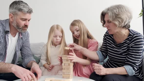 Grandparents Play Tower Game with Two Girls