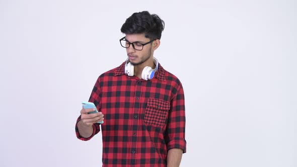 Young Handsome Bearded Indian Hipster Man Using Phone and Looking Surprised