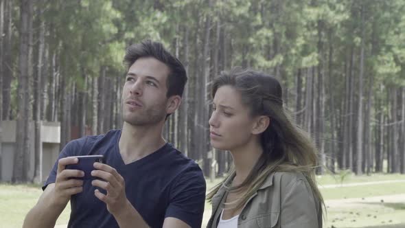 Couple using smart phone to navigate in woods