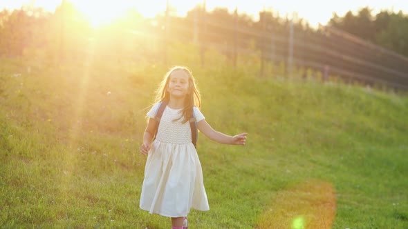 Elementary Schoolgirl Runs Jumping on Grass After Classes