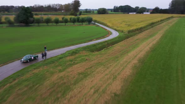 Aerial view of an old car racing in the countryside.
