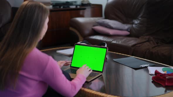 Blurred Young Woman Sitting on the Left Typing on Green Screen Laptop Keyboard