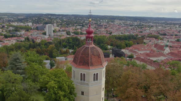 Aerial view close up orbit around historic hilltop Glokenturm tower on Graz's Schloßberg with views