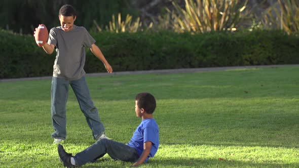 Big Brother Playing a Trick on Little Brother as He Tries to Kick a Football