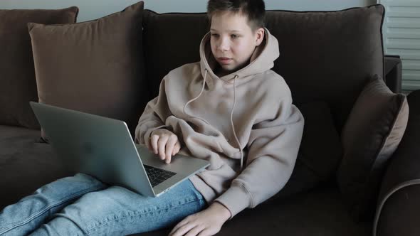 Teenage Boy Using Laptop Laying on the Couch