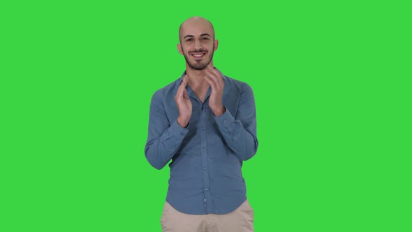 Young Arabic Man Standing Claps His Hands Smiling on a Green Screen, Chroma Key.