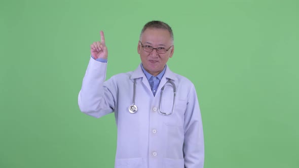 Happy Mature Japanese Man Doctor Pointing Up