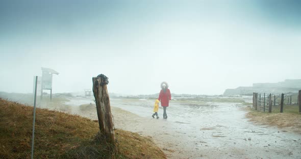 Mother with Her Daughter Walk on Country Road on the Coast