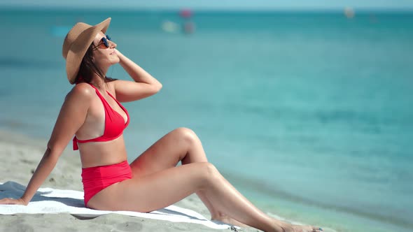Adorable Sexy Fashion Woman in Red Swimsuit Enjoying Sunbathing Sitting on Sand Beach