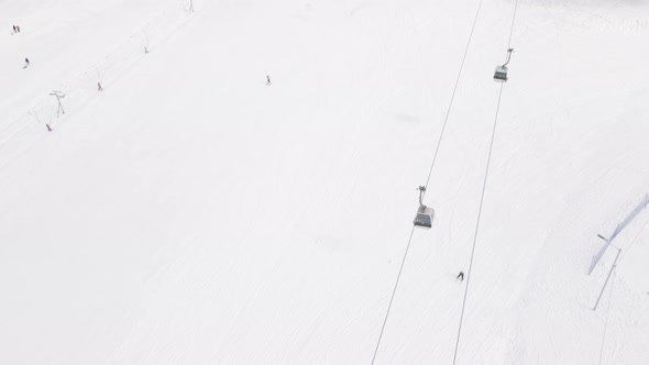 Flying over rope-way with gondolas at mountain resort Crystal Park in Bakuriani. Snowy winter day.