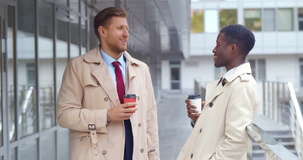 Diverse Smiling Businessmen with Paper Cups Standing Outside Office Building