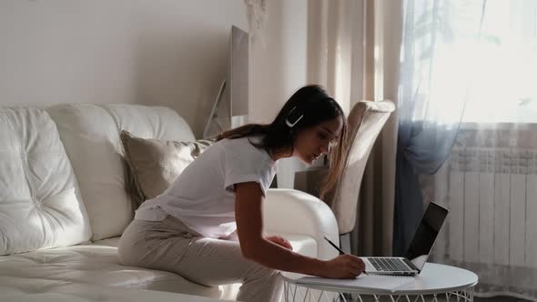 Young Woman Talking on Laptop at Online Conference While Working From Home