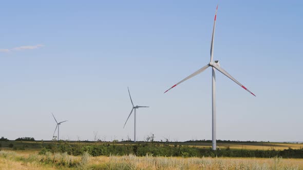 Windmills for Electric Power Production in the Meadow. Group of Windmills for Renewable Electric