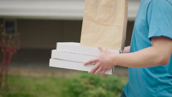 An Unrecognizable Food Delivery Man Carries Pizza Boxes and Food Bags