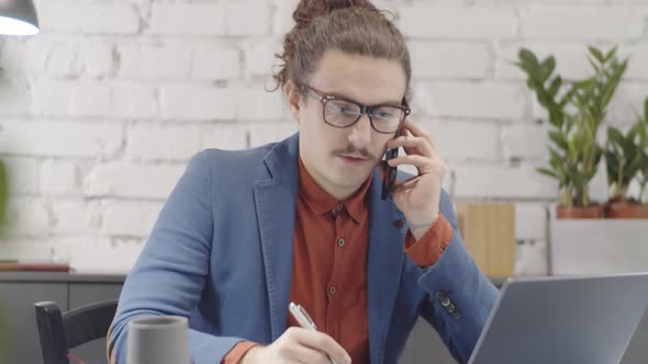 Quirky Businessman Having Important Phone Call at Desk in Loft Office