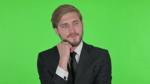 Pensive Young Businessman Thinking and Getting Idea on Green Background