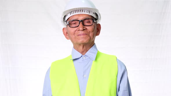 Confident senior engineering architect wearing vest and helmet on white background in studio.