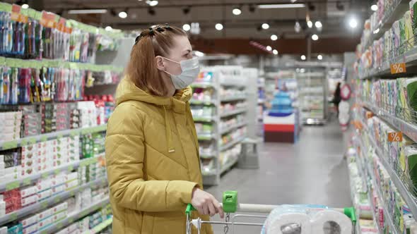 Woman in Protective Medical Mask Chooses Hygiene Items at Supermarket During Covid19 Coronavirus