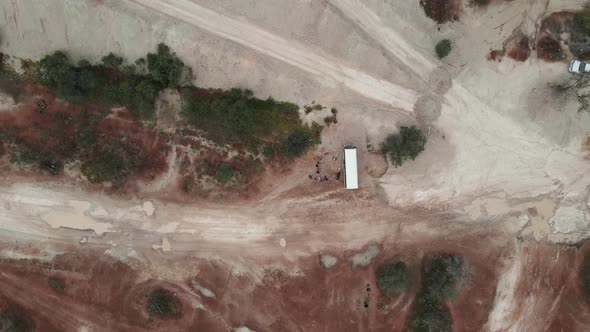 A high view looking down at a tour bus with people surrounded by the colourful rich soil of outback