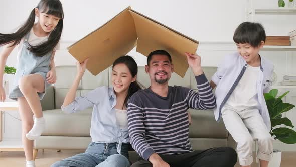 Asian family played in living room and built cardboard house with imagination.