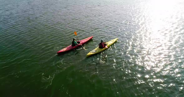 Two kayaks are sailing along a scenic river. Aerial view. Slow motion.