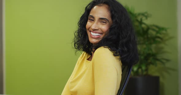 Video of happy biracial woman looking at camera on green background