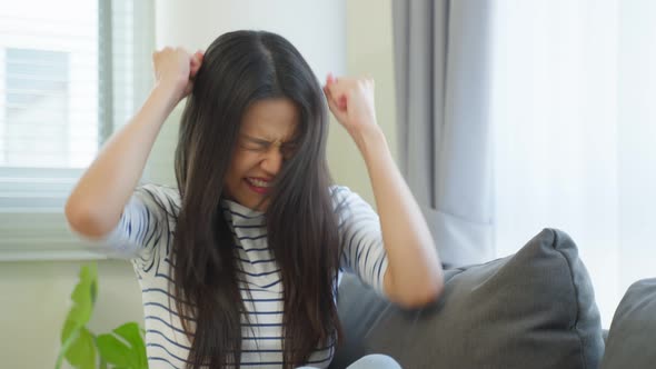 Portrait of Asian young angry woman sit alone on sofa in living room.