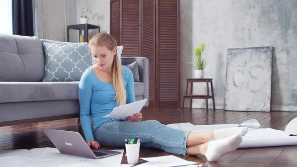 Young woman works with documents using a laptop at home.