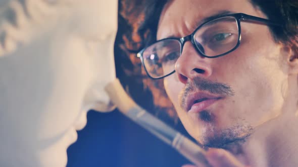 Close Up of Sculptor's Face While Dusting a Bust