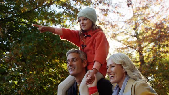 Girl on dads back with mom walking outdoors