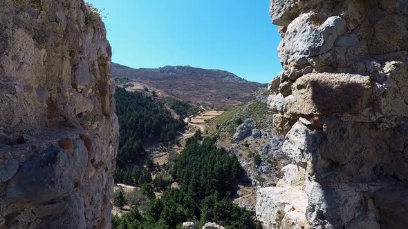 Looking through a gap in the wall of the castle ruins of Paleo Pili an historical site on the island