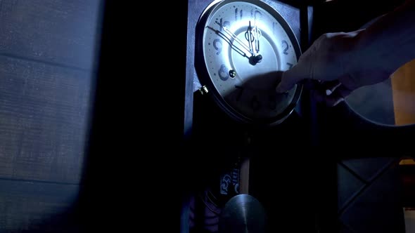 Close up of a  male hand is using the key to the ancient pendulum clock