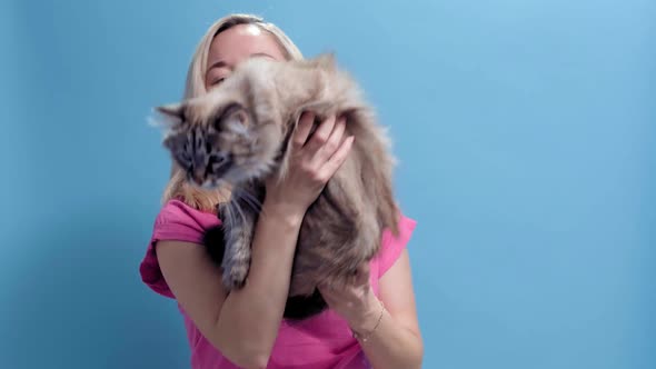 A Young Caucasian Blonde Woman Holds a Cat in Her Hands