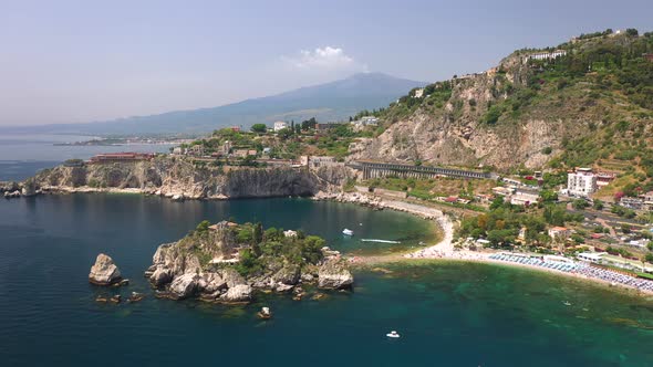 Wide drone shot of Isola Bella flying the Ionian sea. Near Taormina, Sicily, southern Italy.