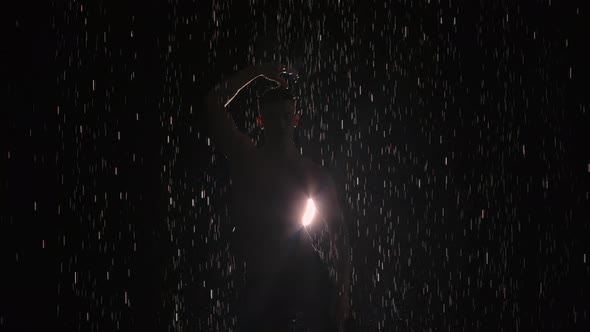 Silhouette of Wet Male Dancer Performing Modern Ballet Dance in Rain and Splashing Water