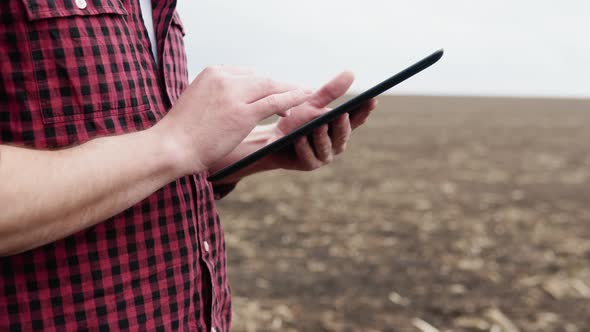 Farmer on a Field with a Tablet Before Planting Agricultural Cultures