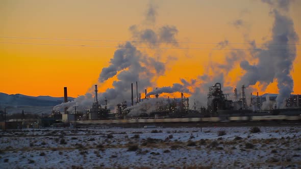 Train going by a factory at sunset