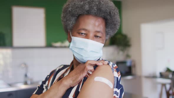 Happy senior african american senior woman showing plaster on arm after covid vaccination