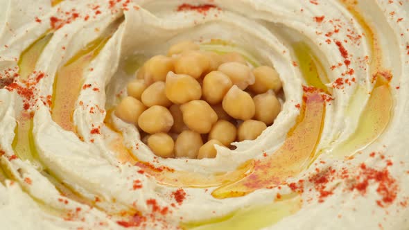 Hummus with smoked paprika, olive oil, whole chickpeas close up, rotation