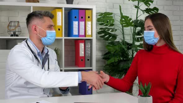 Doctor and patient in protective masks shake hands after agreeing on treatment