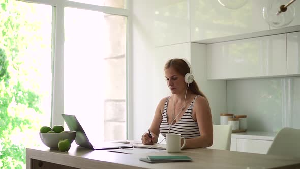 Woman in Headphone Write Note in Notebook Listen to Lecture Webinar and Talk on Video Call Spbd