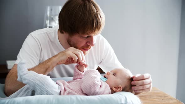 Focused Dad Playing with Lying Baby Daughter