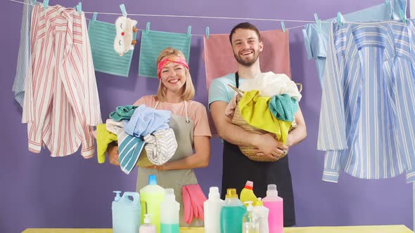 Hardworking Attractive Couple Holding Basket of Laundry and Looking at Camera