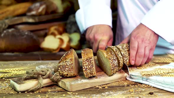 A baker at a Bakery Cuts a Baguette Into Several Pieces