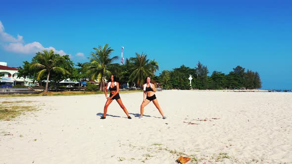 Pretty beauty models relaxing having fun on the beach on sunny blue and white sand background 